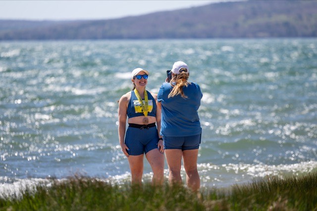 Two finishers with medals at the water's edge
